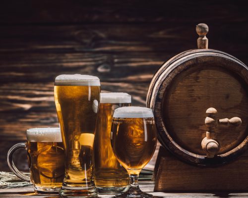 fresh beer in glasses and beer barrel on wooden table, oktoberfest concept